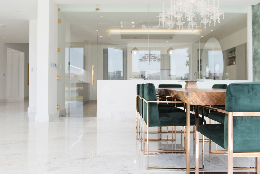 A dining room with white marble floor furnished with bespoke upholstery and a center table.