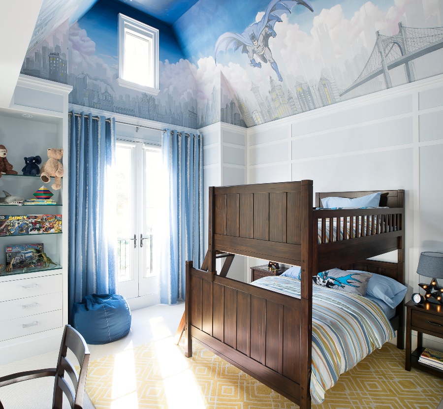 House decorating ideas by Laura Stein Interiors. This kid's bedroom has a painting of the batman on the ceiling, a bed of wood, and curtains in blue.