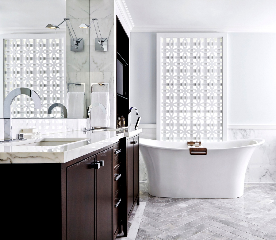 House decorating ideas by Laura Stein Interiors. This white bathroom with white marble floors and white walls has a white bathtub and a vanity in dark wood with a white marble countertop.