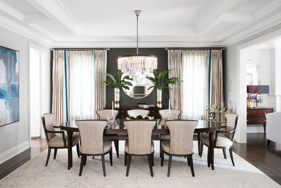 House decorating ideas by Laura Stein Interiors. This modern dining room has one dark wall and the rest is white, an oval wood dining table, and neutral armchairs with a wood structure.