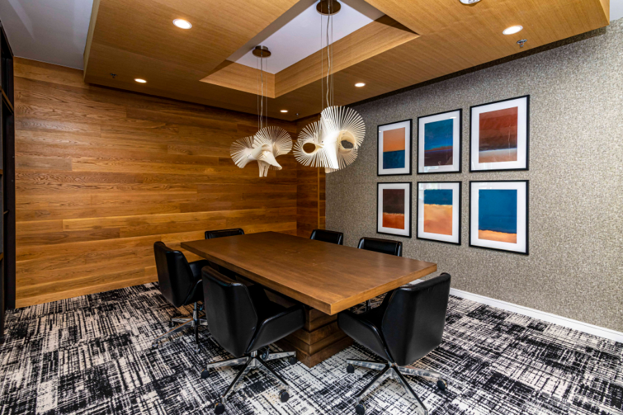 SJL Design Group: Interior Design In Texas. A conference room with a wooden table and seats for six people. There are two suspension lights over the table.
